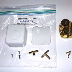 May include: A white music box kit with a gold-colored music mechanism, two white plastic pieces, two gold-colored T-shaped winders, and six gold-colored screws. The kit is packaged in a clear plastic bag with the text "Oaysrey" printed on it.
