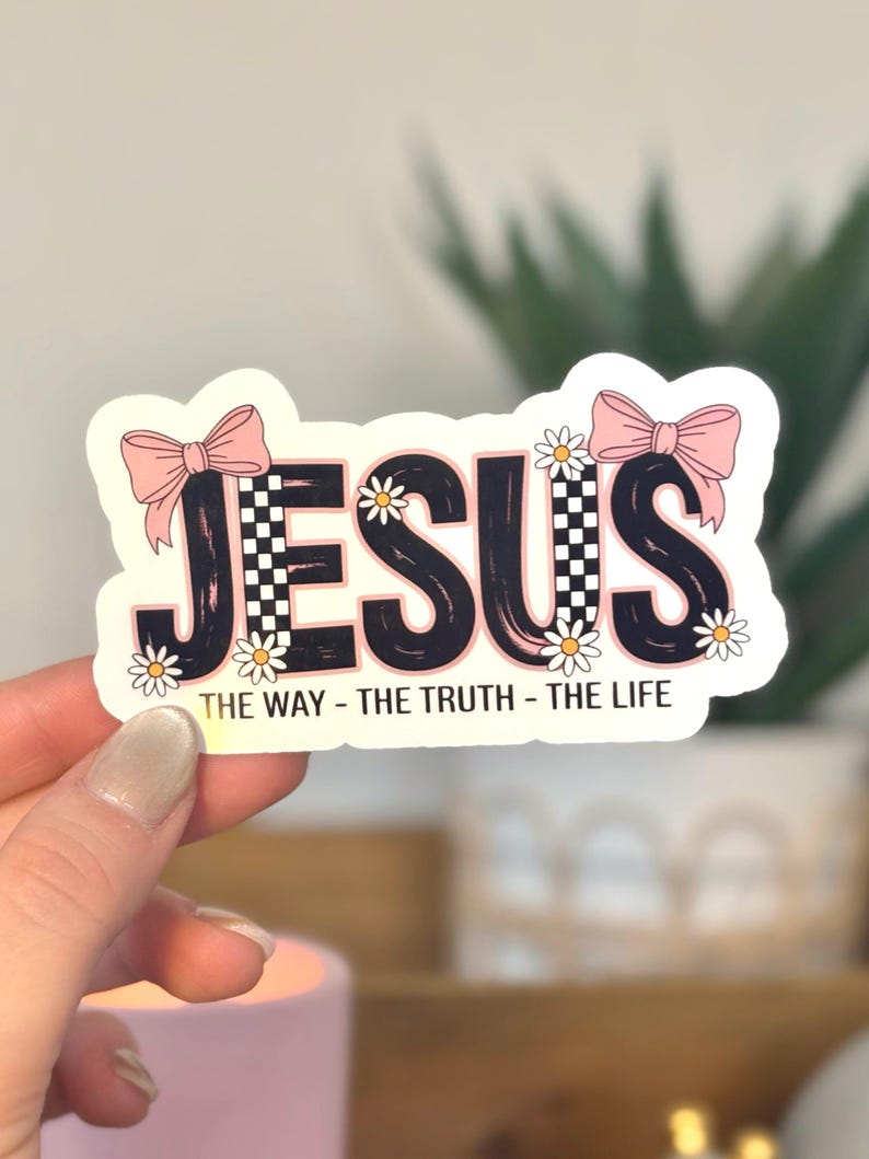 The sticker features the word “JESUS” in bold, playful lettering with a coquette-inspired aesthetic. The design includes pink bows, small daisy flowers, and a trendy checkerboard pattern, giving it a feminine, cute, and modern look. Beneath the main text is the phrase “The Way – The Truth – The Life,” referencing John 14:6.