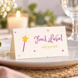 May include: A folded white card with a yellow star-topped pink wand graphic, colorful small star accents, and the magenta text "Food Label" followed by the yellow text "add your text" printed on the front surface of the card.