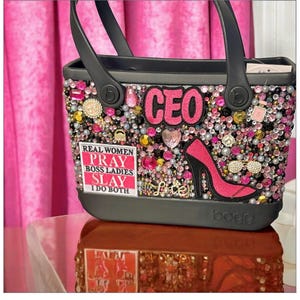 May include: Black tote bag embellished with pink, clear, and gold rhinestones. Features the word "CEO" and a pink high heel. Includes the text "Real Women Pray Boss Ladies Slay I Do Both".