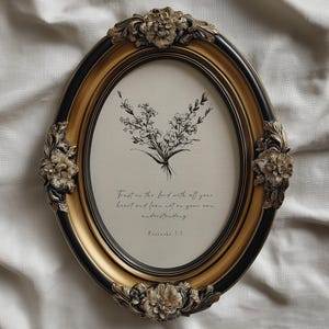 May include: Oval picture frame with a gold and black finish, featuring floral embellishments. The frame holds a print of a floral bouquet and the text "Trust in the Lord with all your heart and lean not on your own understanding. Proverbs 3:5."