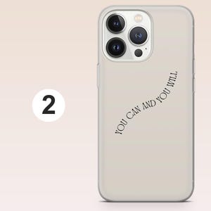 May include: A beige phone case with the words "YOU CAN AND YOU WILL" in a curved, black font. The phone case has a clear border and a camera module with three lenses. A white circle with the number "2" is in the background.