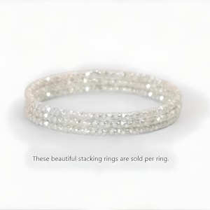 Puede incluir: Un conjunto de tres anillos apilables plateados. Cada anillo está adornado con pequeñas cuentas facetadas, creando un efecto brillante. Los anillos se muestran sobre un fondo blanco, mostrando su delicado diseño. Los anillos se venden individualmente.
