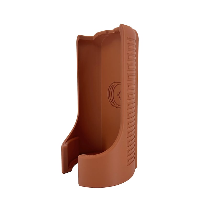May include: A brown, molded plastic holster with a curved design. The holster features a textured pattern on one side and a circular emblem. The open design suggests it is for a specific item.