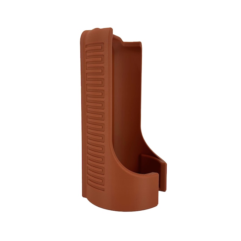 May include: A brown, molded plastic holster with a curved base and a rectangular opening. The holster has a textured, zig-zag pattern on the side. The design is a simple, functional shape.