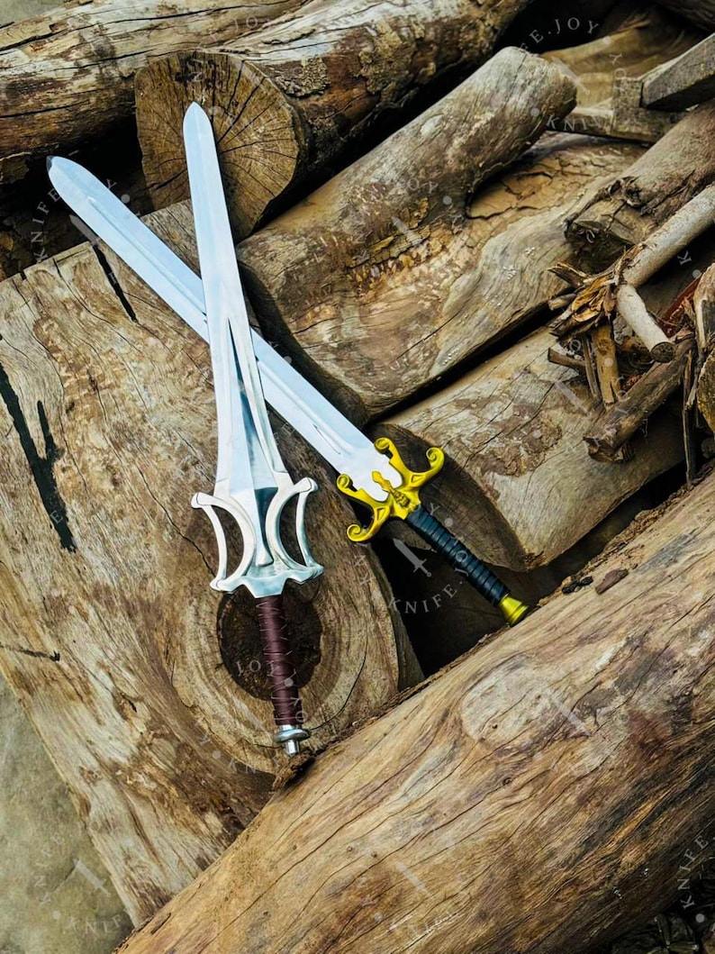 May include: Two decorative swords with silver blades and ornate handles rest on a pile of wooden logs. One sword has a silver and brown handle, while the other features a gold and black handle. The swords are designed with intricate details.