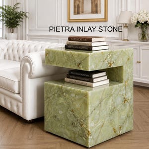 May include: A C-shaped side table crafted from light green stone with natural white and gold veining. The table features a horizontal shelf holding three books titled Classical Art, Renaissance Masterpieces, and The Italian Tradition.