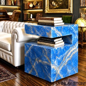 May include: A cubic side table crafted from blue marble with white veining, featuring a horizontal cutout shelf. Two stacks of books are placed on the table, with titles including Classical Art, Renaissance Masterpieces, and The Grand Tour.