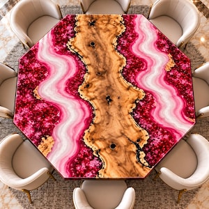 Könnte beinhalten: Ein achteckiger Esstisch mit einer zentralen Holzplatte mit Naturkante, flankiert von leuchtend pinkfarbenen und weißen Abschnitten aus Achat-Optik-Harz, umgeben von acht cremefarbenen Polsterstühlen mit goldfarbenen Metallbeinen.