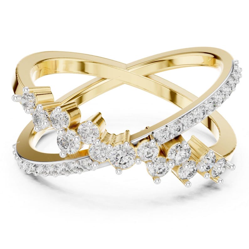 K&ouml;nnte beinhalten: Ein goldfarbener Ring mit einem Kreuz-Design. Ein Band ist mit kleinen, klaren Edelsteinen besetzt, w&auml;hrend das andere eine Ansammlung gr&ouml;&szlig;erer, klarer Edelsteine aufweist. Der Ring ist vor einem wei&szlig;en Hintergrund platziert.