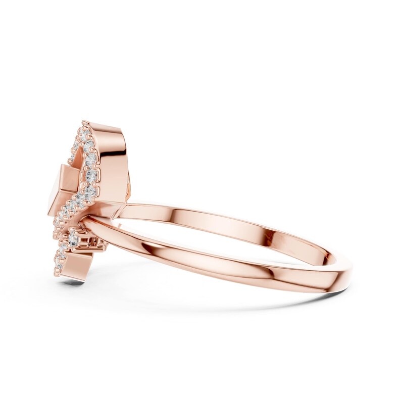 May include: Rose gold ring with a unique design. The ring features a central, rectangular-shaped stone, surrounded by smaller, sparkling stones. The band is a simple, polished rose gold. The ring is set against a white background.