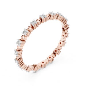 Puede incluir: Anillo de oro rosa con un patrón repetitivo de pequeños diamantes de talla cuadrada engastados en un diseño floral. El anillo tiene una apariencia delicada y elegante, perfecto para el uso diario o ocasiones especiales.