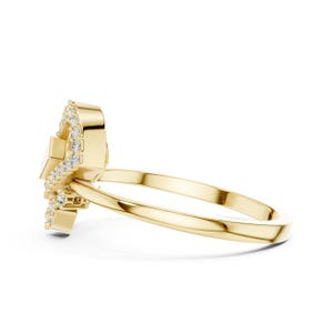 May include: A side view of a gold ring with a unique design. The ring features a central, rectangular-shaped stone and is adorned with small, sparkling diamonds. The band is a simple, polished gold.