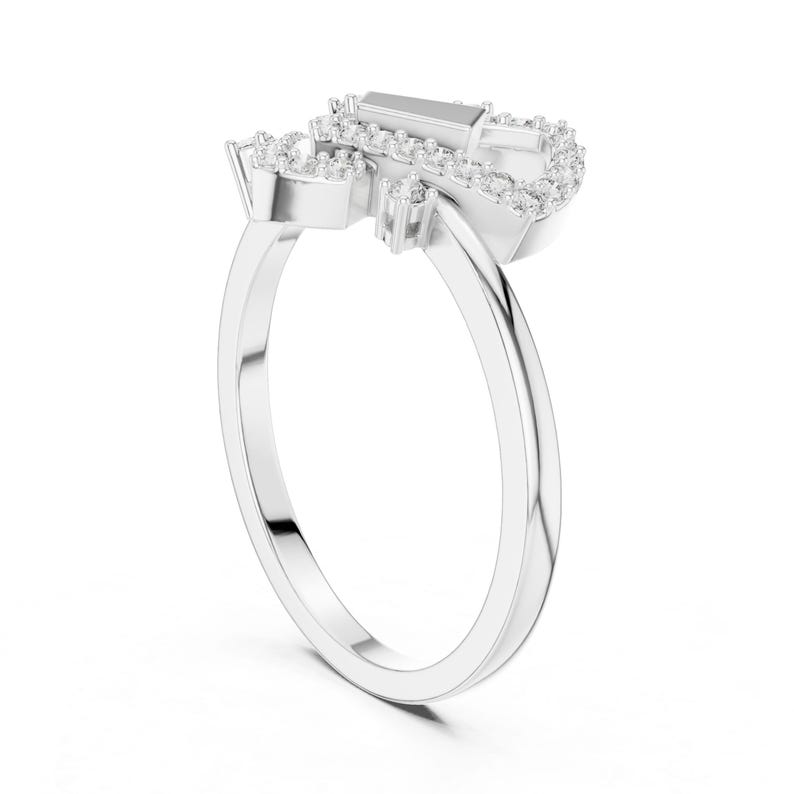 May include: A silver ring with a unique design, featuring a cluster of small, sparkling stones around a larger, rectangular stone. The ring's band is smooth and polished, creating a modern and elegant look.