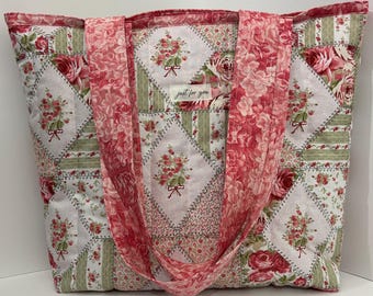 Könnte beinhalten: Eine gesteppte Tragetasche mit einem Blumenmuster in Rosa-, Rot- und Grüntönen. Die Tasche hat ein Patchwork-Design mit rautenförmigen Blumenmotiven und einen einfarbigen rosa Riemen. Auf dem Etikett steht "just for you".