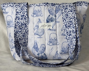 Könnte beinhalten: Weiße Tragetasche mit blauem Hühner- und Eier-Muster. Die Tasche hat blau gemusterte Träger und Verzierungen. Der Text "just for you" befindet sich auf einem weißen Etikett auf der Vorderseite der Tasche.