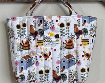 May include: A quilted tote bag with a farm-themed pattern. The white fabric features roosters, sunflowers, and small blue houses. The bag has a yellow button closure and the text "just for you".