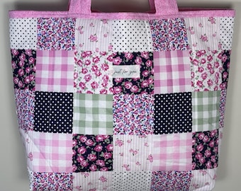 Könnte beinhalten: Eine Patchwork-Tragetasche mit verschiedenen Blumen-, Tupfen- und Vichy-Mustern in Rosa, Weiß und Marineblau. Die Tasche hat rosa Griffe und Verzierungen, und der Text "just for you" ist auf der Vorderseite sichtbar.