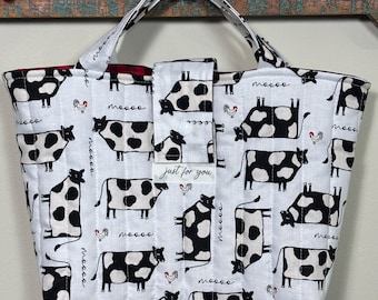 Könnte beinhalten: Weißer Shopper mit einem schwarz-weißen Kuhmuster, rotem Karofutter und zwei Griffen. Die Tasche hat eine Klappe mit dem Text "just for you".