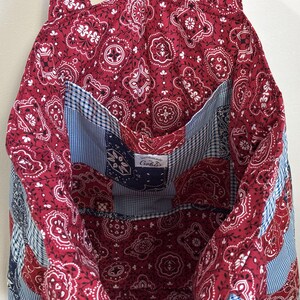 May include: A handmade tote bag with a red paisley pattern and white details. The interior has a blue and white gingham pocket and a blue and white paisley pocket. The label reads "Handmade by Gobis".