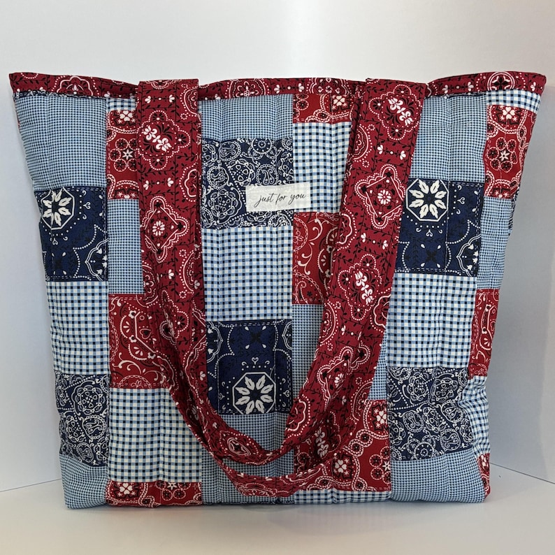 May include: A large patchwork tote bag featuring red paisley, navy blue floral, and light blue gingham patterns. The bag has two handles and a tag that reads "just for you".