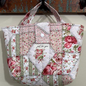 May include: Quilted tote bag with a patchwork design featuring floral patterns in shades of pink, red, and green. The bag has a button closure and a handle. The text "just for you" is visible on the front.