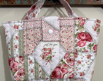 May include: Patchwork tote bag with floral patterns in pink, red, and green. The bag has a button closure and a handle. The text "just for you" is visible on the front. The bag is made of quilted fabric.