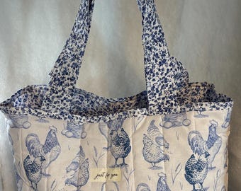 Könnte beinhalten: Gesteppte Tragetasche mit blau-weißem Hühnerdruck. Die Tasche hat ein Blumenmuster auf den Henkeln und der Innenverkleidung. Die Tasche hat eine rechteckige Form und ein Etikett mit der Aufschrift "just for you".