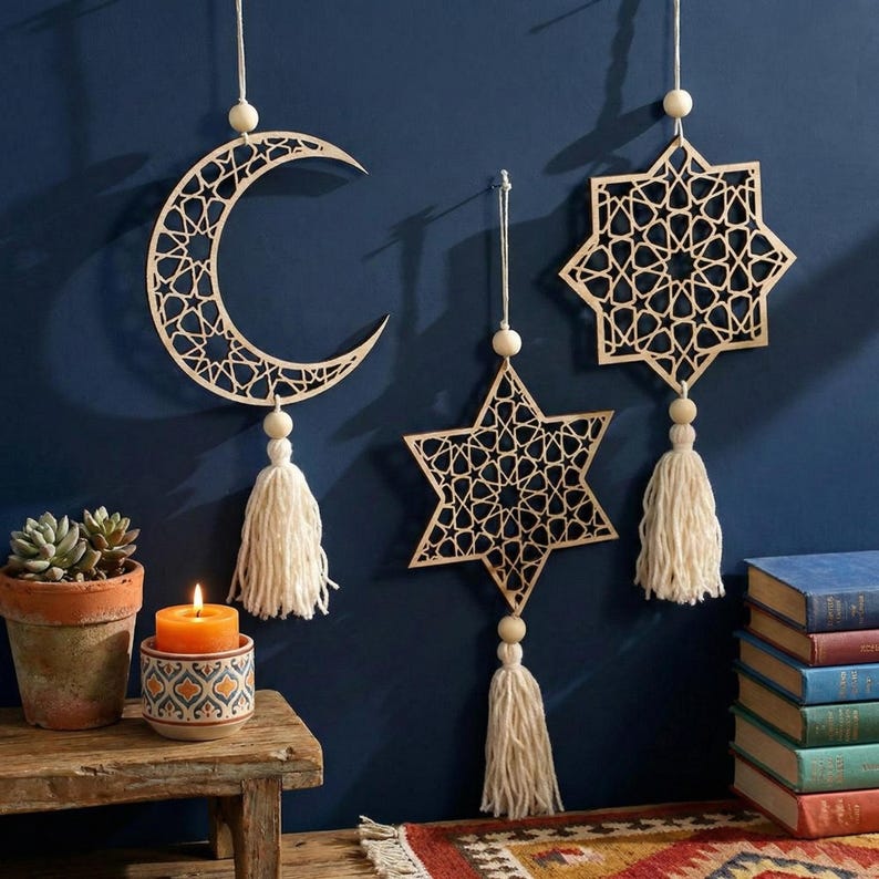 May include: Three wooden hanging decorations: a crescent moon, a five-pointed star, and an eight-pointed star. Each has a detailed geometric pattern, a tassel, and a wooden bead. They hang against a dark blue wall.