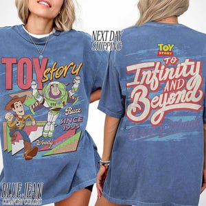 K&ouml;nnte beinhalten: Blaues Jeans-T-Shirt mit dem Toy Story-Logo und den Figuren Woody und Buzz Lightyear. Auf der Vorderseite des Shirts stehen "Toy Story" und "Buzz Since 1995". Auf der R&uuml;ckseite des Shirts steht "To Infinity and Beyond".