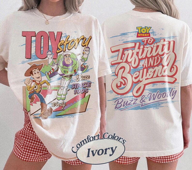 K&ouml;nnte beinhalten: Cremefarbenes T-Shirt mit den Toy Story-Charakteren Woody und Buzz Lightyear. Der vordere Aufdruck zeigt "Toy Story" und "Buzz Since 1995". Auf der R&uuml;ckseite steht "To Infinity and Beyond" und "Buzz & Woody".