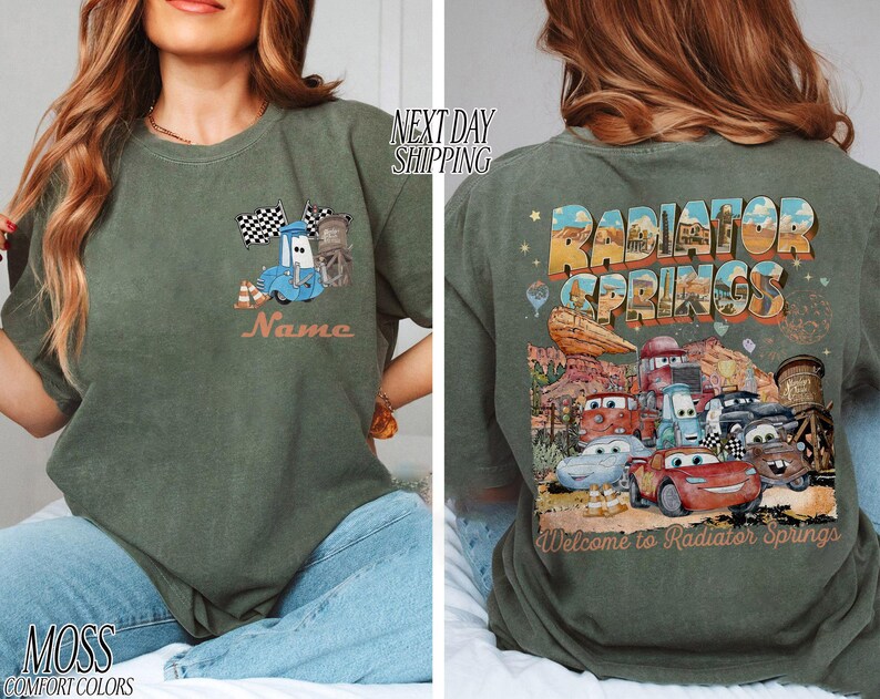 Puede incluir: Camiseta verde musgo con un dise&ntilde;o de coche de dibujos animados y el texto "Name" en la parte delantera. La parte trasera de la camiseta muestra "Radiator Springs" con varios personajes de coches y la frase "Welcome to Radiator Springs".