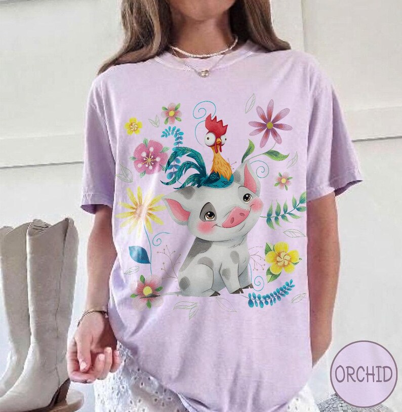 Pu&ograve; includere: T-shirt lilla con un design a fumetto di maiale e gallo, circondato da fiori e foglie. L'immagine &egrave; stampata su una maglietta a maniche corte, ideale per l'uso quotidiano.