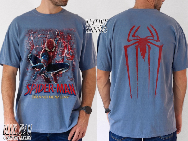 以下が含まれることがあります： スパイダーマンが描かれたブルージーンズのTシャツ。前面には、スパイダーマンがアクションを起こしているグラフィックと「Spider-Man Brand New Day」の文字が描かれています。Tシャツの背面には赤いクモのシンボルが表示されています。