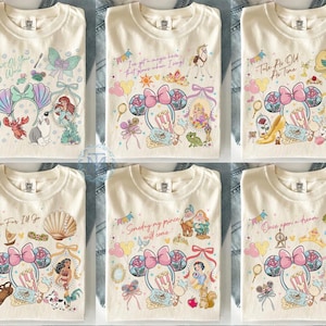 May include: Cream-colored t-shirts with various Disney princess-themed designs. Each shirt features a different princess, along with related imagery and text. Designs include Ariel, Rapunzel, Belle, Moana, Snow White, and Cinderella.