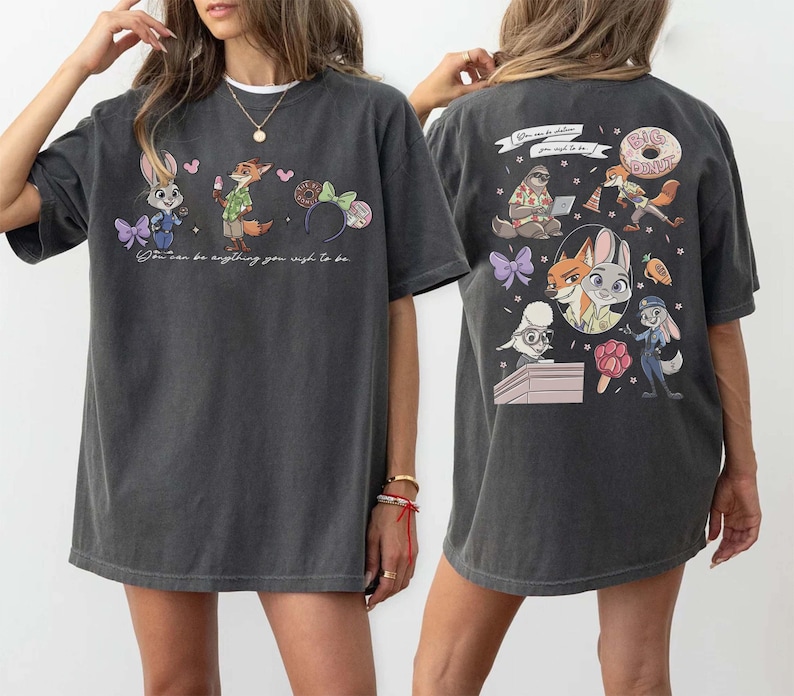 Puede incluir: Camiseta gris oscuro con personajes de dibujos animados de Zootopia. La parte delantera muestra a Judy Hopps, Nick Wilde y unas orejas de Minnie. La parte trasera presenta m&aacute;s personajes de Zootopia y la frase "You can be anything you wish to be."