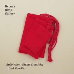 May include: Three red velvet drawstring pouches with rose red cords. The pouches are stacked on top of each other. The text "Ruby Valor - Divine Creativity" and "Cord: Rose Red" is printed below the pouches.