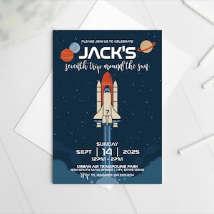 Può includere: Un biglietto d'invito blu navy a tema spaziale. La carta presenta un razzo spaziale, pianeti e stelle su uno sfondo blu scuro. Il testo include "Jack's seventh trip around the sun" e i dettagli dell'evento.