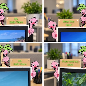 May include: A monitor topper featuring a pink flamingo standing by a palm tree and a second flamingo peeking from the side. A rectangular sign is attached, displaying phrases such as Oh, Hello There, How You Doin, or If you need me, Don't.