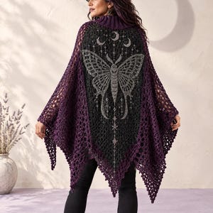 Puede incluir: Un poncho de ganchillo en color morado oscuro y negro con un gráfico de polilla grande en la espalda. La prenda tiene una textura de punto abierto similar a una red con un dobladillo en punta. Sobre la polilla, tres lunas y estrellas.