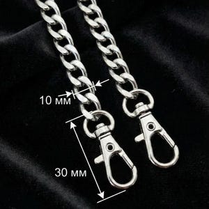May include: Silver-colored chain with two lobster claw clasps. The chain links are 10 mm wide, and the clasps are 30 mm long. The chain is displayed against a black background.