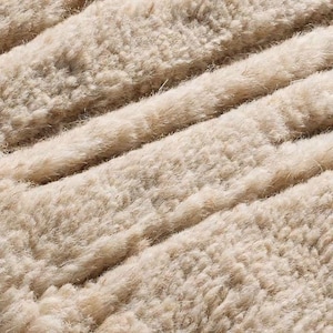 Puede incluir: Primer plano de una tela beige texturizada con crestas diagonales en relieve. El material parece suave y afelpado, con una superficie ligeramente irregular. El color es un tono c&aacute;lido y neutro, lo que sugiere un textil acogedor o natural.
