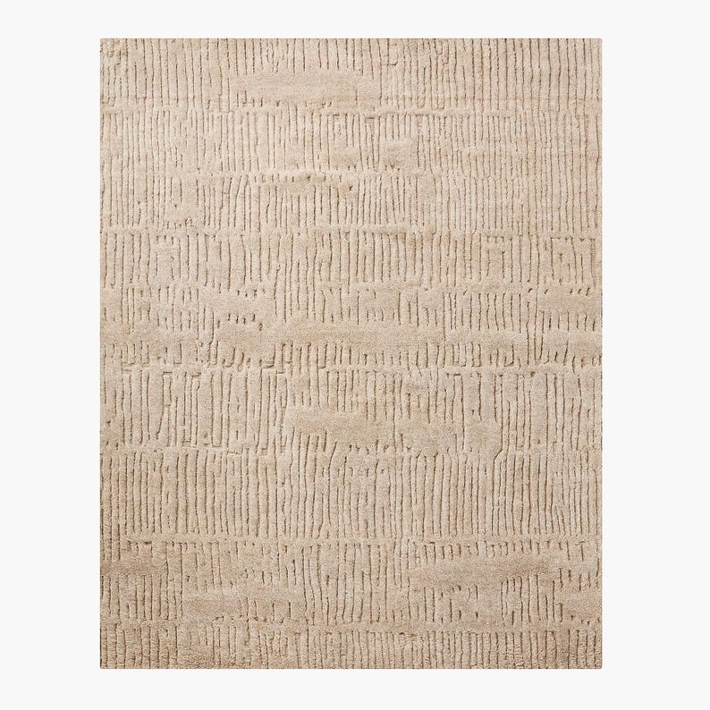 Puede incluir: Alfombra rectangular beige con superficie texturizada. La alfombra presenta un patr&oacute;n de l&iacute;neas verticales, creando un efecto rayado. El color neutro y el dise&ntilde;o sencillo la hacen adecuada para varios estilos de interior.