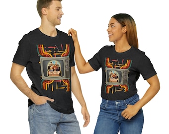 May include: Dark gray t-shirts featuring a retro television graphic with the text "WKRP in Cincinnati." The design includes a colorful array of orange, yellow, and red lines. The shirts are worn by a man and a woman.