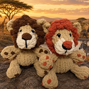 May include: Two plush lion toys made of soft, textured yarn. The left lion has a dark brown mane and brown paw pads. The right lion features a rust-orange mane and matching orange paw pads. Both have cream-colored faces, black embroidered noses, and eyes.