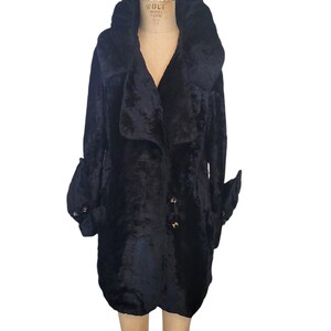 May include: A black, vintage-style coat with a large, ruffled collar and unique sleeve detailing. The coat features a button-down front and a flared, rounded hem. The fabric appears to be a plush, textured material.