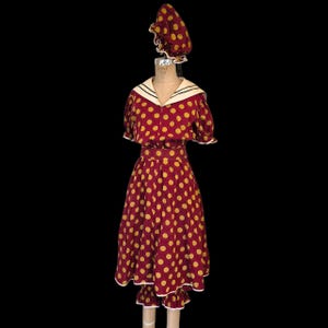Könnte beinhalten: Ein Ensemble im Vintage-Stil mit einem bordeauxfarbenen Kleid mit gelben Punkten, einer passenden Haube und einem Matrosenkragen. Das Kleid hat ein figurbetontes Oberteil, einen ausgestellten Rock und weiße Verzierungen. Die Haube hat einen gerüschten Rand.