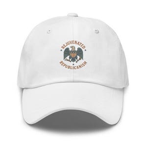 May include: White baseball cap featuring an embroidered emblem of an eagle with the words "Rejuvenated Republicanism" in a circular design. The text and emblem are in shades of brown, blue, and red.