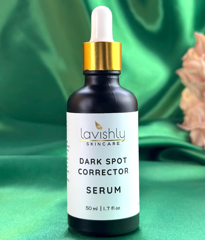 May include: A black skincare serum bottle with a white label featuring the text "Lavishly Skincare Dark Spot Corrector Serum". The bottle has a gold-colored dropper and a white tip. The bottle contains 50 ml / 1.7 fl oz of serum.