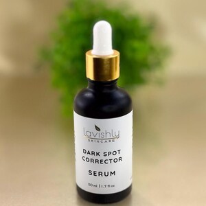 May include: A black skincare serum bottle with a white label featuring the text "Lavishly Skincare Dark Spot Corrector Serum". The bottle has a gold-colored top and a white dropper. The bottle contains 1.7 fl oz of serum.